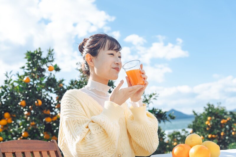 柑橘畑と瀬戸内海を背に生搾りジュースを味わうお客様